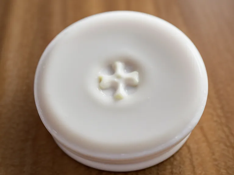 Close-up of a white chewable oral probiotic tablet on a wooden surface.